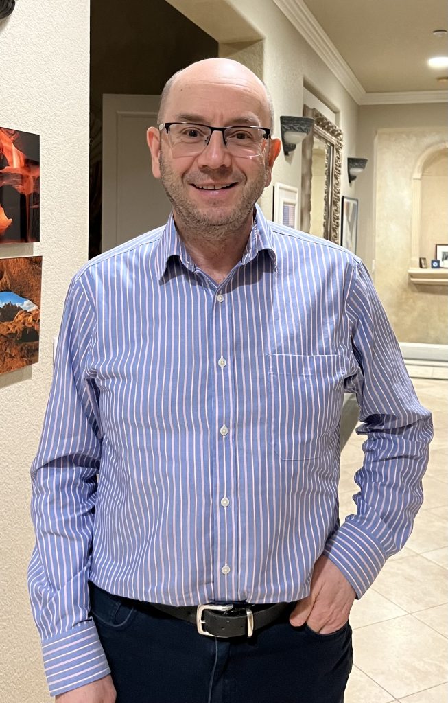 dov smiling wearing a blue with white pinstripe shirt